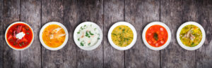 Bowls of different soups with toppings in a line